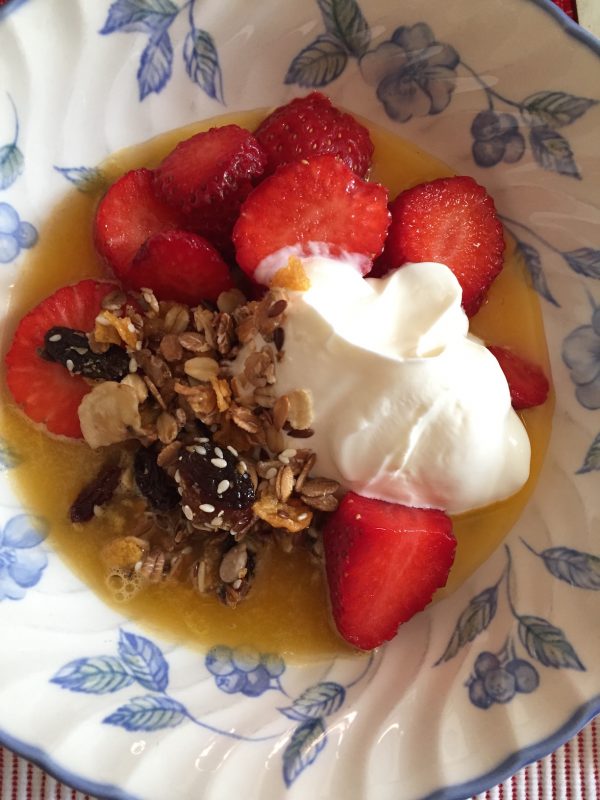 Rapea granola, tuoreet mansikat ja kermavaahto tarjoiltuna herkullisessa lautasessa.