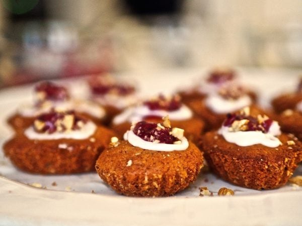 Hunajaiset Runebergin tortut ja kakku, koristeltu kermavaahdolla ja marjoilla.