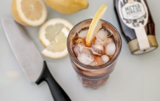 Mustatee-sitruunajäätee juoma, jossa on hunajaa ja sitruunaa, tarjoiltuna jääkylmänä.