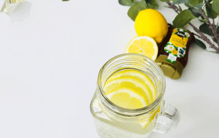 Sitruuna-inkivääri-hunajatee lasissa, raikas ja terveellinen juoma.