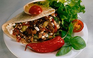 Gourmet tortilla täynnä maukasta täytettä ja tuoreita vihanneksia, tarjoiltuna raikkaan salaatin kan.