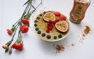 Hunajainen smoothie- ja marjainen bowl, koristeltu passionhedelmä, vadelmat ja mustikat.