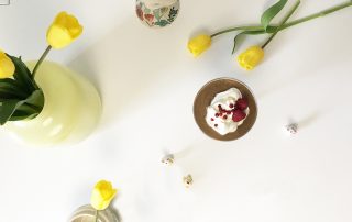 Mämmiä ja marjahilloa tarjoiltuna, taustalla keltainen kukkakimppu ja koriste-esineitä.