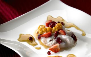 Hunajainen marjarahka ja tuoreet marjat, tarjoiltuna kauniilla lautasella.