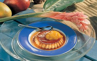 Hunajainen vanukas tarjoiltuna sinisellä lautasella, päällä keltainen hedelmäkomeetti.