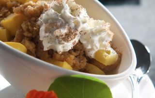 Omenacobbler jälkiruoka kermavaahdolla ja kanelilla, herkullinen ja raikas makuelämys.