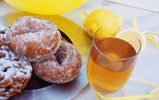 Sima ja donitsit tarjoiltuna juhlapöydässä, sitruuna ja keltainen koriste.