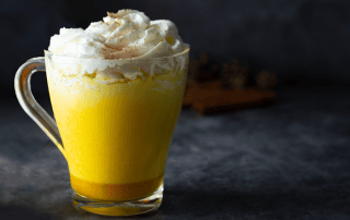 Hunajainen kanelitee kuumassa lasissa, päällystetty kermavaahdolla.