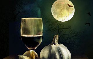 Kuvassa halloween-juoma, jossa punainen viini, kurpitsa ja täysikuu taustalla.